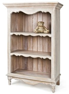 a wooden book shelf with a teddy bear on top