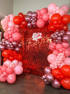 the balloon arch is decorated with red, silver and pink balloons