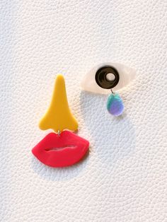 a pair of colorful earrings sitting on top of a white surface next to a button