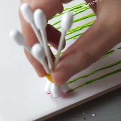 someone is making something out of paper with white and green stripes on it's surface