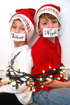 two young boys wearing christmas hats with their mouths taped to each other's faces