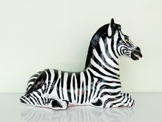 a black and white zebra statue sitting on top of a table next to a wall