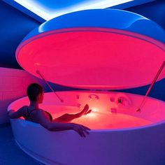 a man sitting in a bathtub that is lit up with red and blue lights