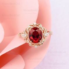 a close up view of a ring with a red stone in the center and two diamonds around it