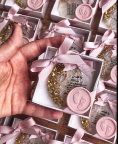 a person's hand next to some pink and gold baby footprints in small boxes