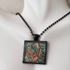 a black necklace with a green and orange design on it