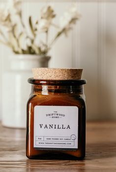 a jar of sweet whiskey sits on a table next to a vase with flowers in it