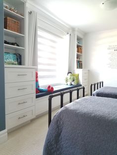 two beds in a room with white walls and blue bedding, along with bookshelves