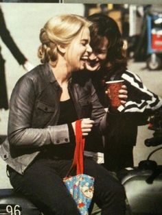 two women sitting next to each other on a motorcycle with a cup in their hand