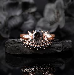 a black diamond ring sitting on top of a piece of wood with flowers in the background