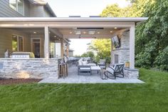 an outdoor living area with patio furniture and stone wall, surrounded by lush green grass