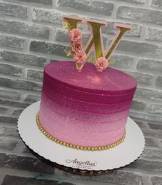 a pink and gold ombrella cake with the letter w on it's top