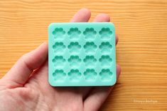 a hand holding a plastic mold that looks like an ice tray with holes in it