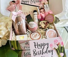 a birthday gift box filled with personal care products and flowers on a table next to a card that says happy birthday