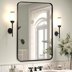 a bathroom sink with a large mirror over it's top and lights on the wall