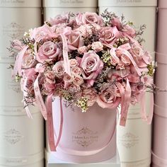 a pink hat box filled with lots of pink flowers and ribbon tied around the top