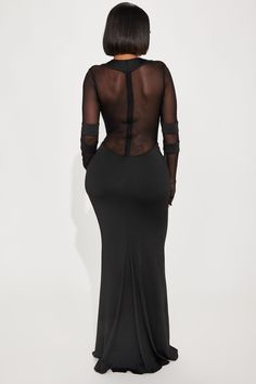 the back of a woman wearing a black dress with sheer sleeves and an open neckline