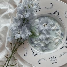 blue flowers are in a bowl on a white plate