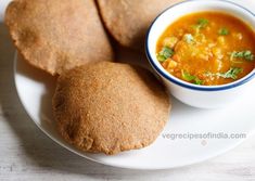 three pita breads on a white plate with a bowl of soup in the middle