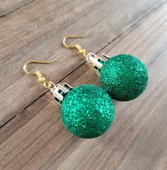 18k gold plated stainless steel earrings with lightweight green glitter Christmas ornament. These earrings are flashy, elegant, and perfect for showing off your Christmas spirit this holiday season. The ornament balls are hollow made from a light plastic, which are durable but are not heavy on the ears, and are coated in fine glitter to achieve the classic green sparkle of a Christmas tree decorative ornament. They are shatterproof, lightweight, and dazzling for this holiday!  Be sure to check out more HANDMADE jewelry in my shop, DizzleBees, beautiful jewelry of all kinds available! Made with quality materials and always nickel and lead free metals ♡ Perfect gift for a friend or loved one: All jewelry pieces are packaged in silver silk jewelry pouches, wrapped carefully, and packaged with Orb Earrings, Christmas Tree Glitter, Ornament Earrings, Glitter Ball, Silk Jewelry, Globe Ornament, Jewelry Pouches, Silver Silk, Ball Earrings