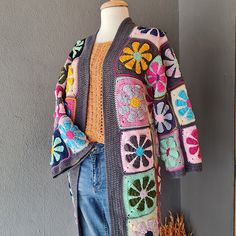 a crocheted jacket with flowers on the front and back, sitting on a mannequin's head