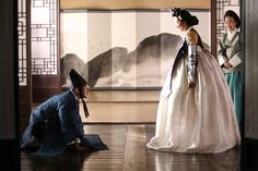 two women dressed in traditional japanese clothing standing next to each other and looking at something on the ground