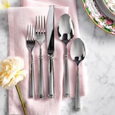 a set of five silverware on a pink napkin next to a flower