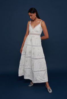 This V neck maxi dress features delicate lace panels and trim at the neckline and hem, as well as a flattering silhouette and embroidered palm trees made with small sequins, beads and pearls.  A perfect example of Waimari’s understated elegance. Summer Embellished Lace Midi Dress, Summer Embellished Floor-length Midi Dress, Floor-length Embellished Midi Dress For Summer, White V-neck Maxi Dress With Lace Trim, White Elegant Maxi Dress With Lace Trim, Elegant White Maxi Dress With Lace Work, White Maxi Length Dress With Lace Trim, Midi Length Dresses With Cutwork Hem For Vacation, White Lace Work Midi Dress