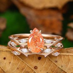 an orange and white diamond ring sitting on top of a leaf