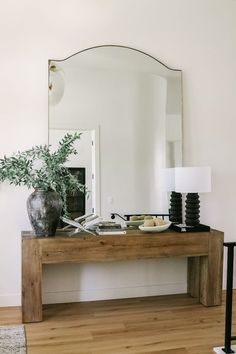 a wooden table topped with a mirror next to a plant