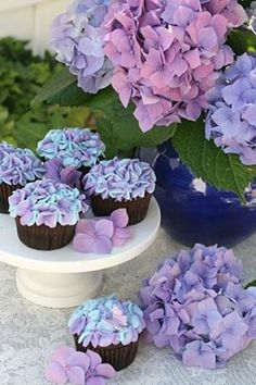 purple flowers are being used to decorate cupcakes