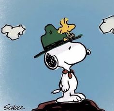 a cartoon dog wearing a green hat and standing on top of a rock with clouds in the background