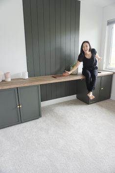 a woman sitting on top of a desk next to a window in an empty room