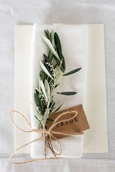 the napkins are wrapped in twine and tied together with an olive leaf tag