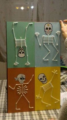 a person holding up a piece of paper with skeletons on it and two people in different colors