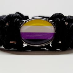 a black bracelet with a purple, yellow and white stripe on it