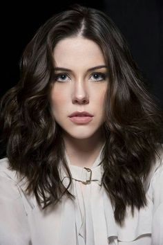 a woman with long dark hair wearing a white shirt