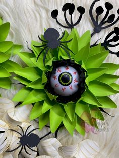 an eyeball surrounded by green leaves and black spider legs on a white fur background