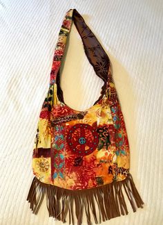 "Super cool. 100% up-cycled, cross-body shoulder bag! Exterior of this bag is multi colored corduroy, colors of red, brown, orange, yellow, gold, and turquoise. Brown sued fringe across the bottom, red felt peace sign with wooden  turquoise and copper beads. 2 tiny pockets on the back of the bag. Closes with a cocnut shell bead and brown satin ribbon. The interior is brown embossed velvet, with a beautiful daisy design! Stitched into the strap are the words \"Love and compassion are necessities, Embossed Velvet, Words Love, Daisy Design, Brown Satin, Red Felt, Boho Bag, One Bag, Shell Beads, Brown Orange