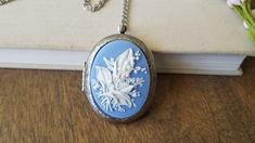 "A beautiful detailed light blue and white floral cameo is set into a bright silver finish locket. Perfect for photos, mementos, or just as lovely as is. The locket measures approx. 1.9'' x 1.4'' (48mm x 35mm) and holds space for two special photos. Cameo is 40mmx 30mm. 30\" silver finish silver plated chain with lobster claw clasp as shown. Comes ready to gift." Formal Blue Locket Jewelry, Blue Medallion Jewelry For Anniversary, Blue Medallion Necklace For Anniversary, Victorian Blue Cameo Jewelry, Blue Locket Jewelry For Anniversary, Blue Victorian Locket Jewelry, Victorian Blue Locket Jewelry, Antique Blue Locket Jewelry, Blue Cameo Jewelry For Wedding