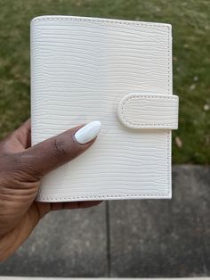 a hand holding an empty white leather notebook