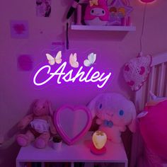 there is a neon sign that says ashley on the wall next to stuffed animals