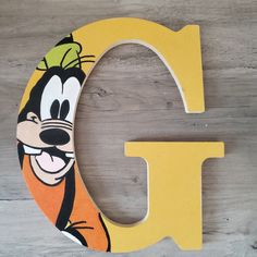 the letter c is painted yellow and has goofy face on it's upper half