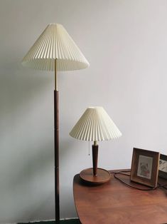 two lamps sitting on top of a wooden table next to a framed photo and lamp shade