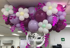 balloons and flowers are hanging from the ceiling in an office building with people standing around