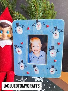 an elf is next to a blue frame with snowmen on it