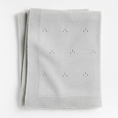 a white knitted blanket with small dots on the front and bottom, folded in two rows