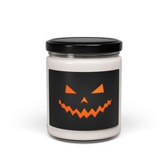 a candle with an orange jack - o'- lantern face on the front and black lid