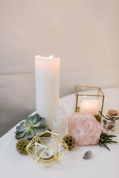 a white table topped with a lit candle and other decorative items next to each other