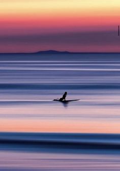 a person on a surfboard in the ocean at sunset